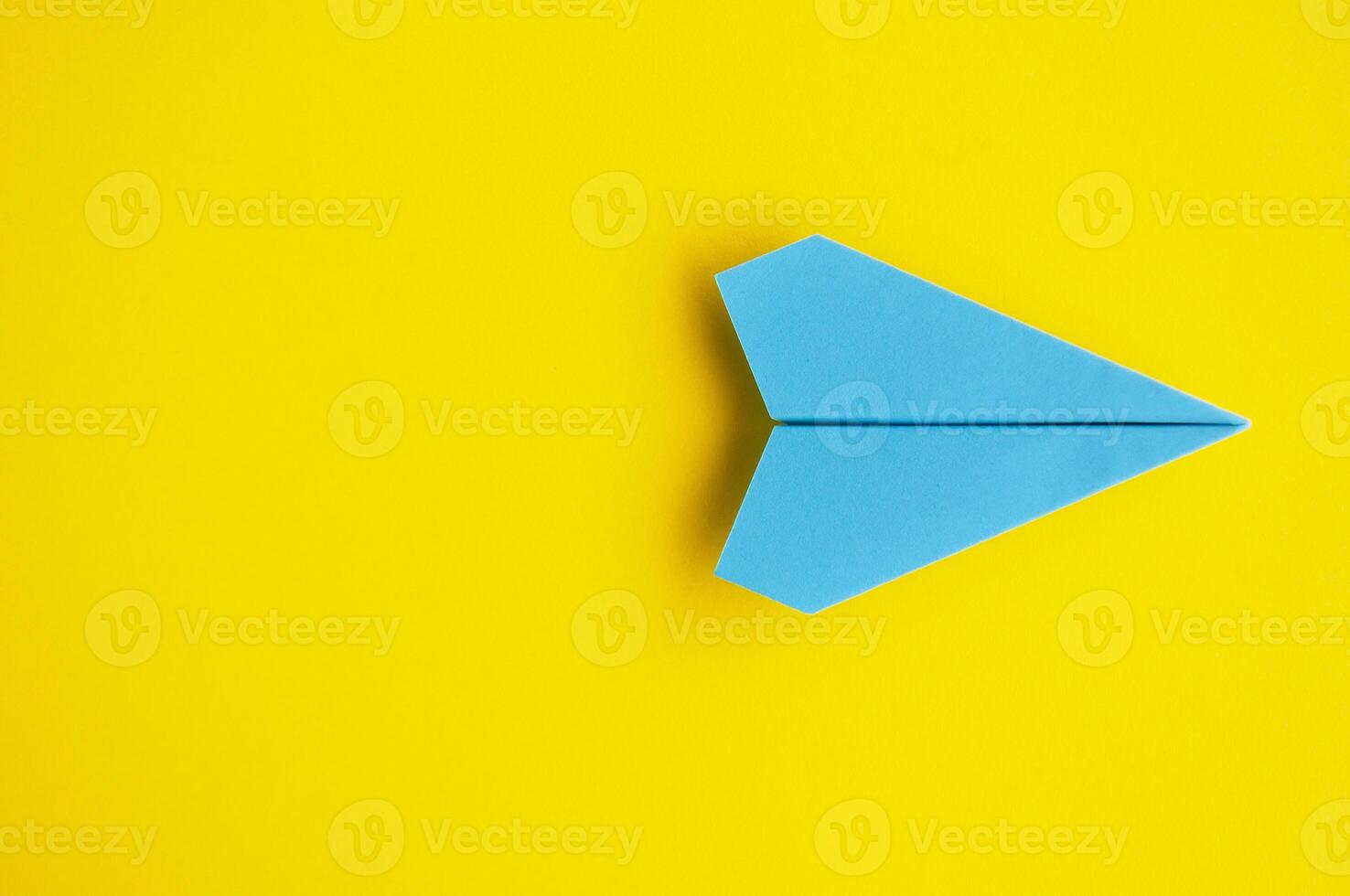 Top view of blue paper airplane with customizable space for text or ideas on yellow cover background photo
