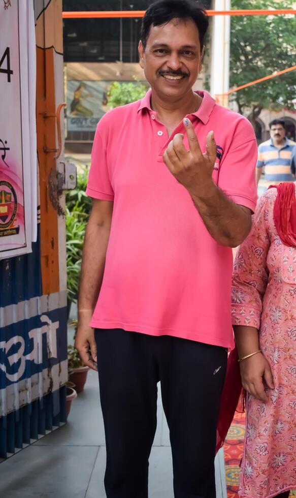 New Delhi, India - May 25 2024 - Unidentified people showing their ink-marked fingers after casting votes in front of polling booth of east Delhi area for general Lok Sabha Elections 2024 photo