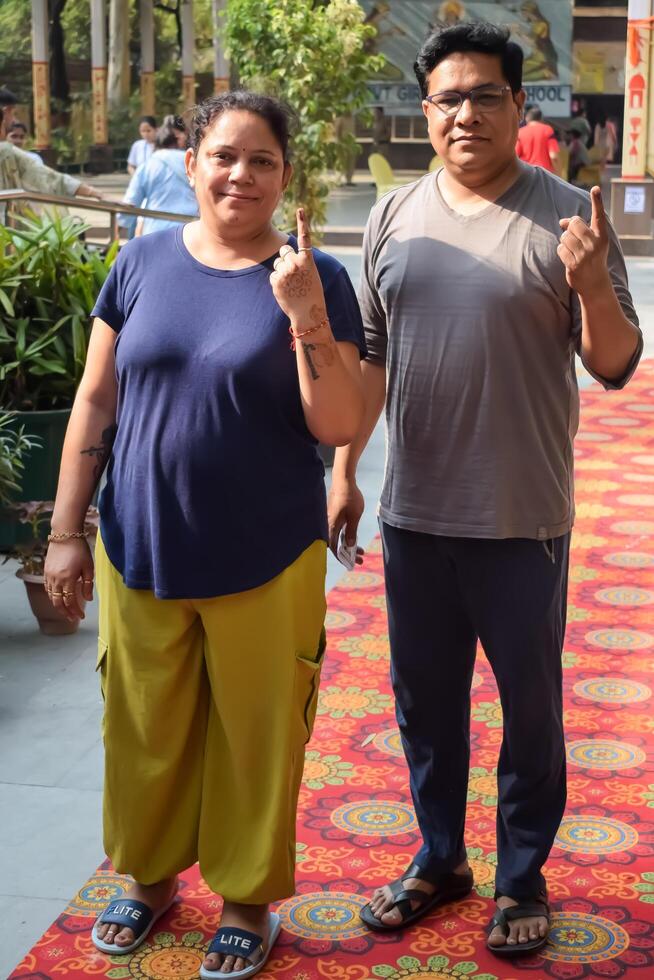 New Delhi, India - May 25 2024 - Unidentified people showing their ink-marked fingers after casting votes in front of polling booth of east Delhi area for general Lok Sabha Elections 2024 photo