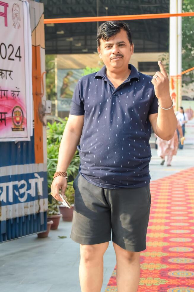 New Delhi, India - May 25 2024 - Unidentified people showing their ink-marked fingers after casting votes in front of polling booth of east Delhi area for general Lok Sabha Elections 2024 photo