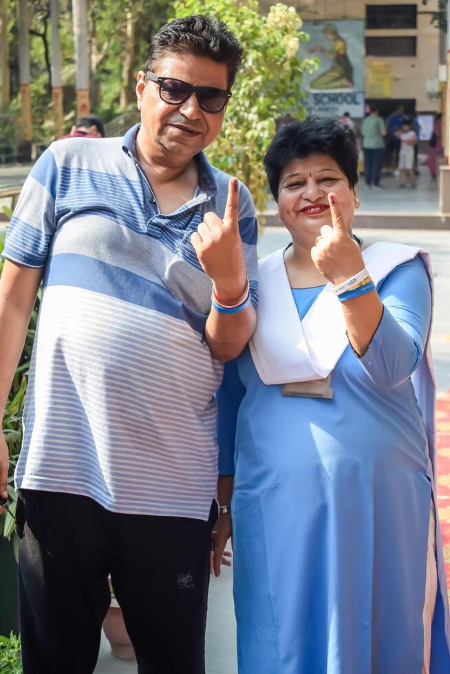 New Delhi, India - May 25 2024 - Unidentified people showing their ink-marked fingers after casting votes in front of polling booth of east Delhi area for general Lok Sabha Elections 2024 photo