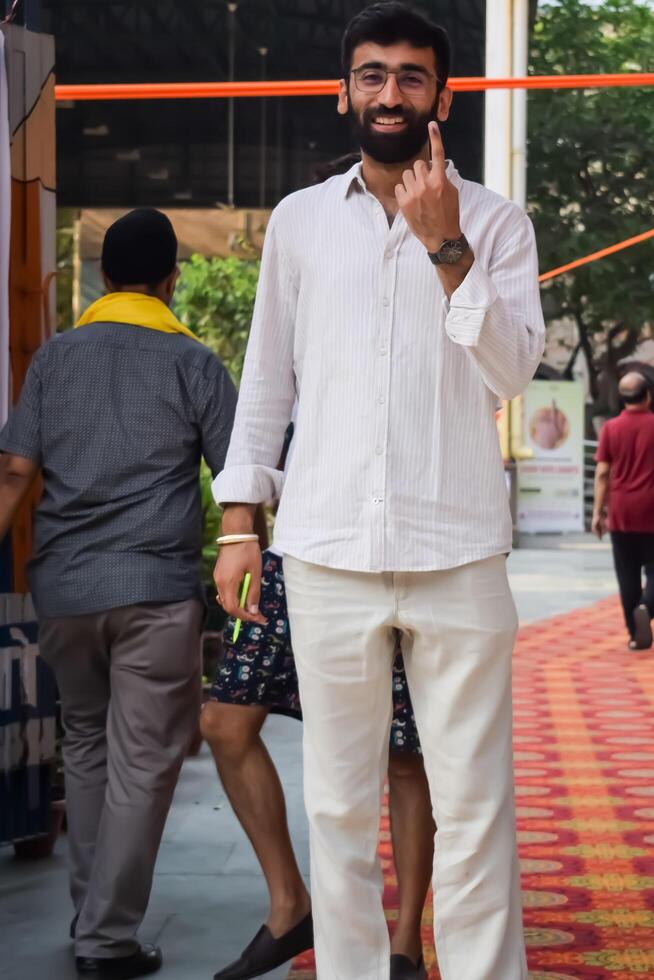 New Delhi, India - May 25 2024 - Unidentified people showing their ink-marked fingers after casting votes in front of polling booth of east Delhi area for general Lok Sabha Elections 2024 photo