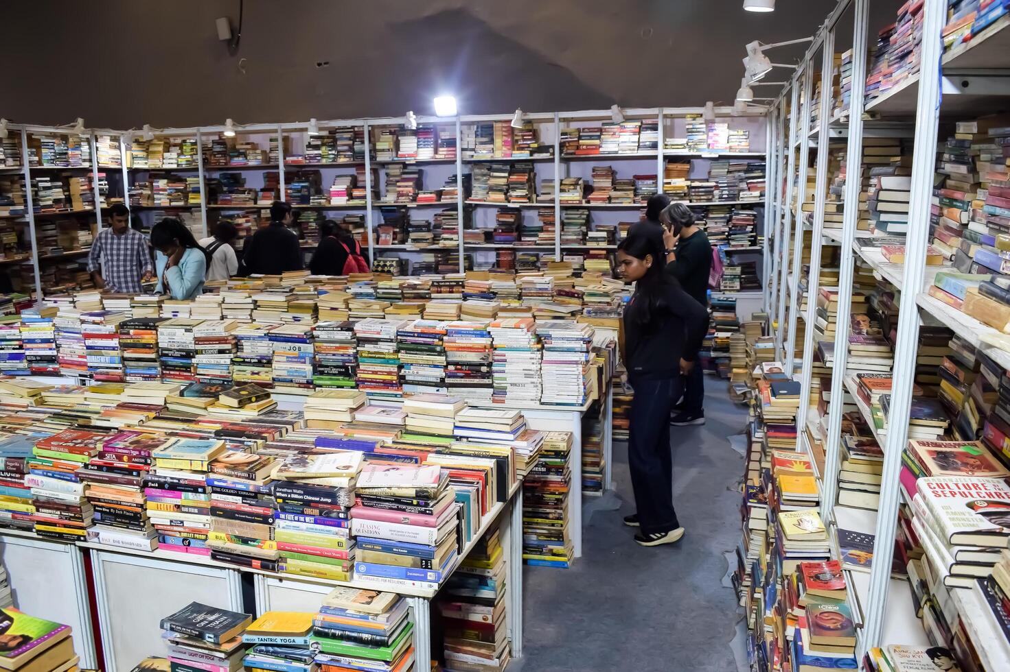 Delhi, India, July 17 2024 - Various age group people reading variety of Books on shelf inside a book-stall at Delhi International Book Fair, Books in Annual Book Fair at Bharat Mandapam complex photo