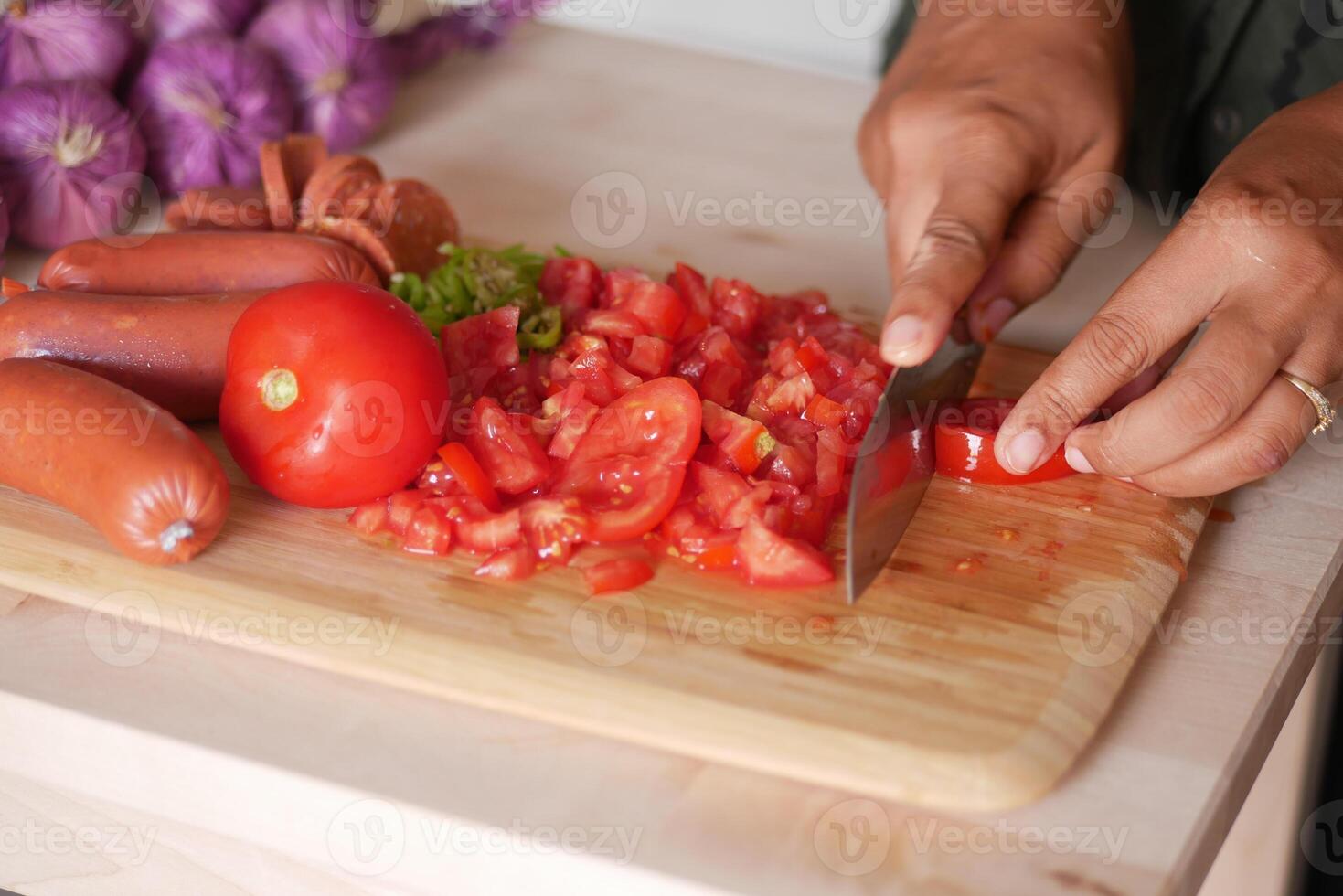 cutting fresh tomato on a chopping board at kitchen photo