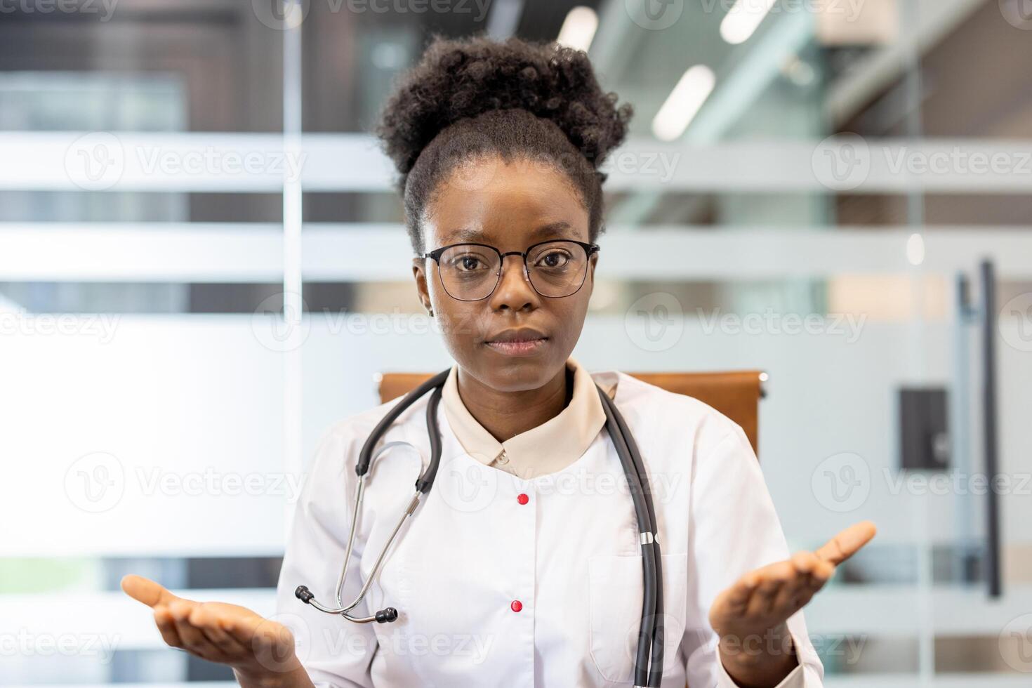 Female doctor wearing glasses and stethoscope in medical office gesturing confusion or uncertainty, capturing emotion professional setting. Ideal for healthcare, medical, and consulting concepts. photo