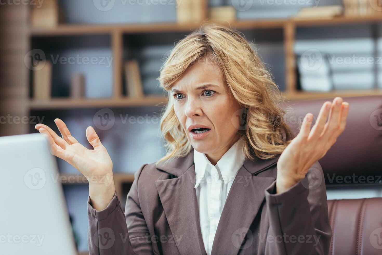 An exasperated mature female executive experiences trouble while working from her stylish home office setting. photo