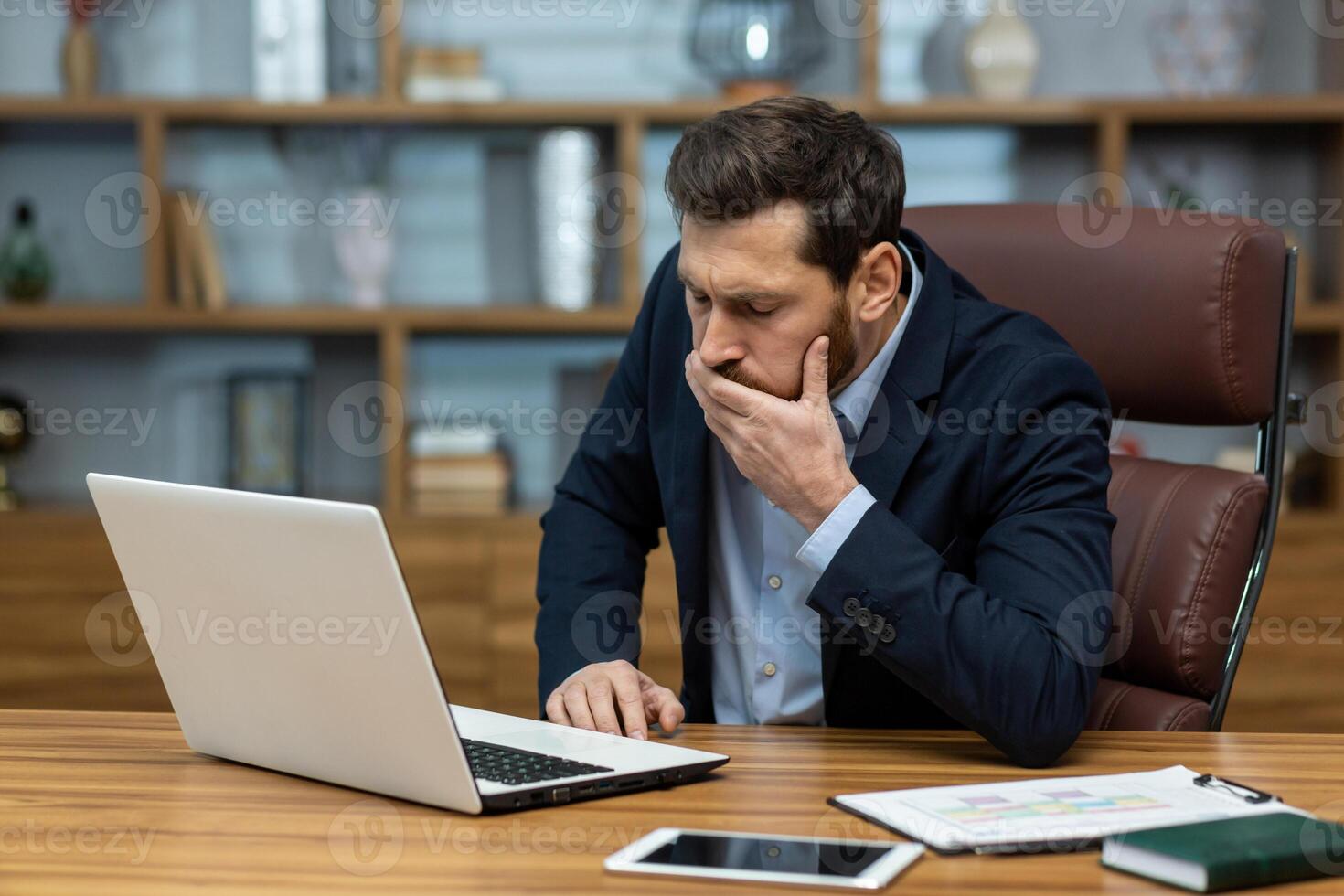 Sick office worker sitting by desk with pc and leaning on table while covering mouth from nausea with hand. Well dressed male having digestion problems symptoms and vomiting due to food poisoning. photo