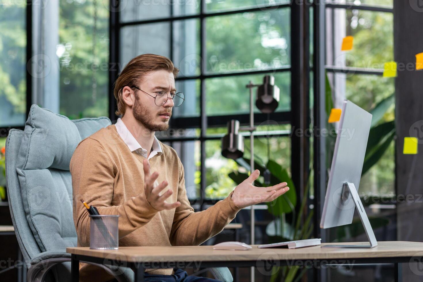 Frustrated and upset businessman reading news online from computer monitor, young blond man sad at workplace inside office in casual clothes unhappy with results. photo