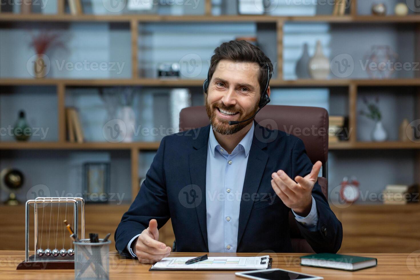 Experienced mature man in a suit and headset working from a well-organized home office, exuding confidence and charisma. photo
