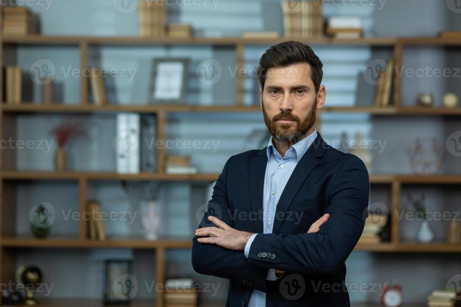 Serious middle age man looking at camera with disapproving facial expression and folded arms indoors. Strict boss in formal clothes thinking about choices and getting ready making important decisions. photo