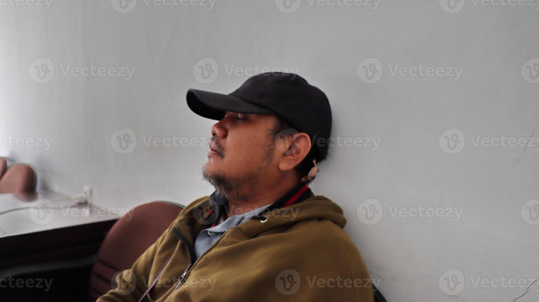 an adult man leeping exhaustedly leaning against the wall photo