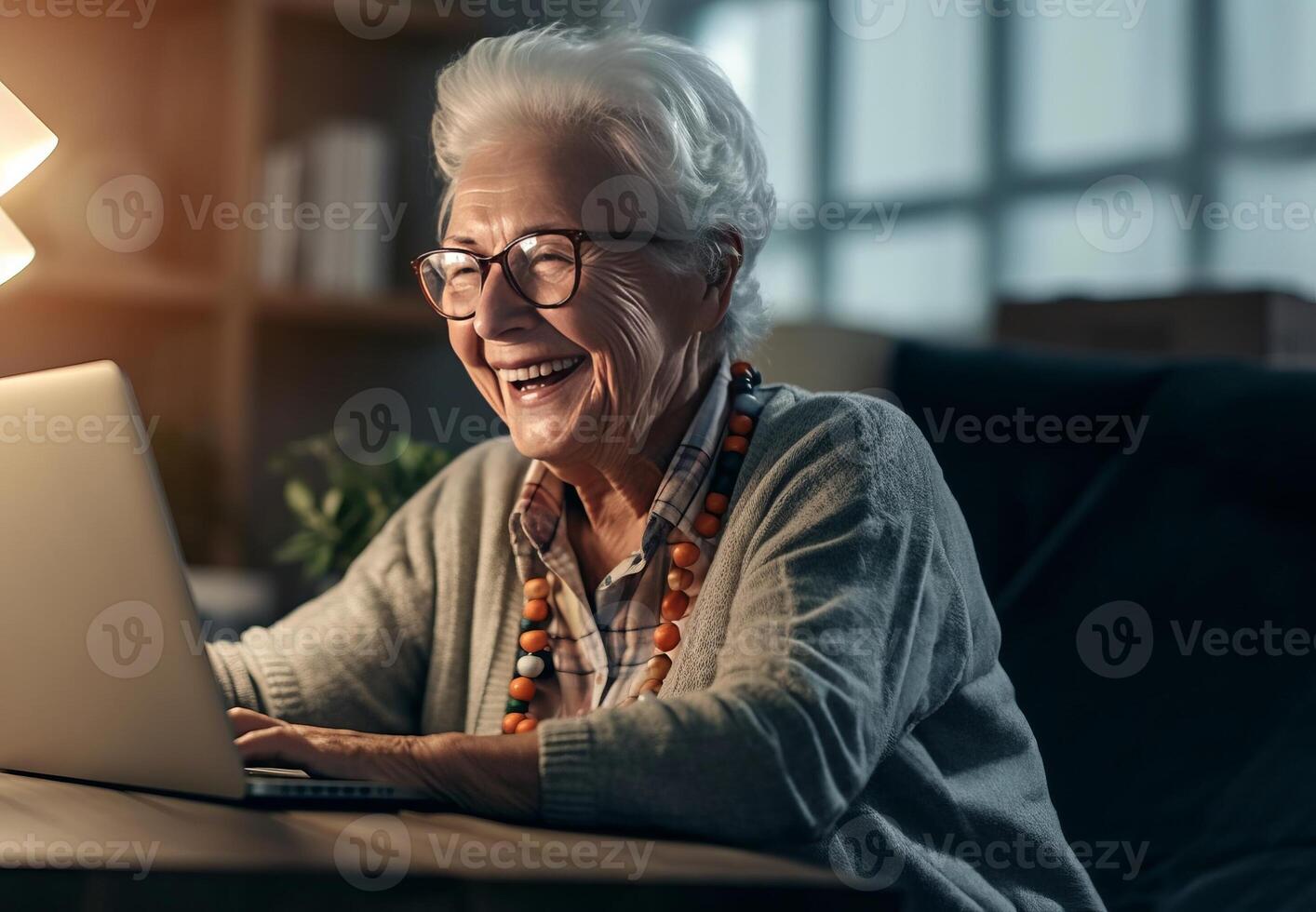 Radiant senior woman enjoys the warmth of her home, smiling while using a laptop, embracing the comfort of modern technology photo