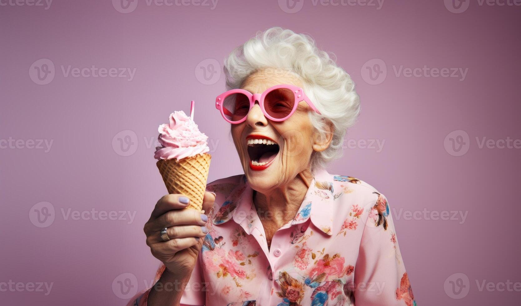 An elegant older woman, adorned with stylish sunglasses, enjoys a moment of indulgence as she savors ice cream, creating a vibrant and modern image against an isolated pink background photo