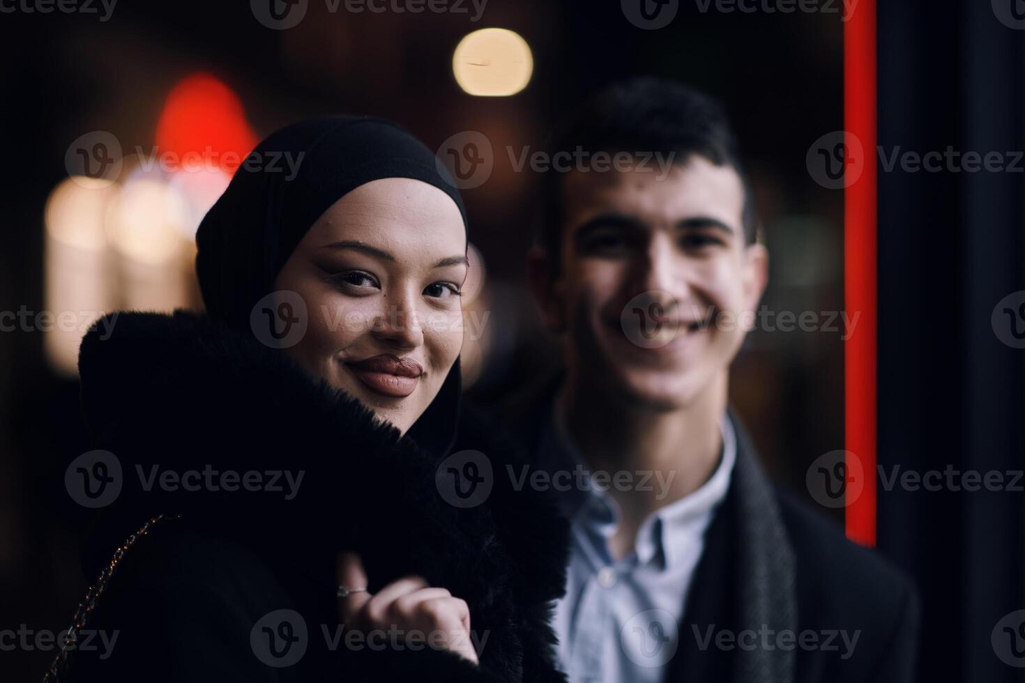 Happy multicultural business couple walking together outdoors in an urban city street at night near a jewelry shopping store window. photo