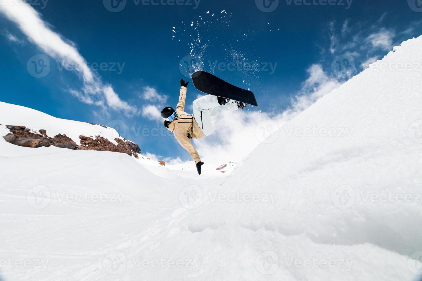 Snowboarder performs a trick in a jump, snow flies behind the athlete. Ski resort in the snow photo