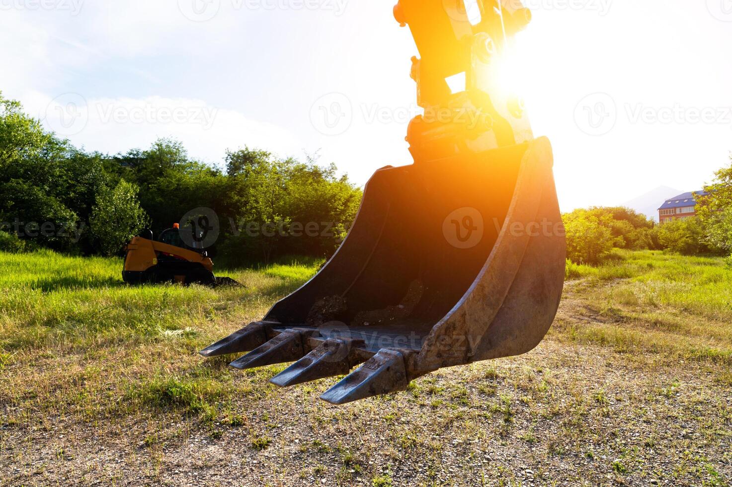 Close-up of an excavator bucket against the background of the setting sun. Excavator equipment earthworks concept photo
