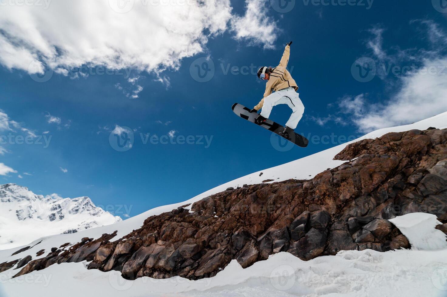 Professional snowboarder jumps high into the air from the kicker, taking the board with his hand while flying photo