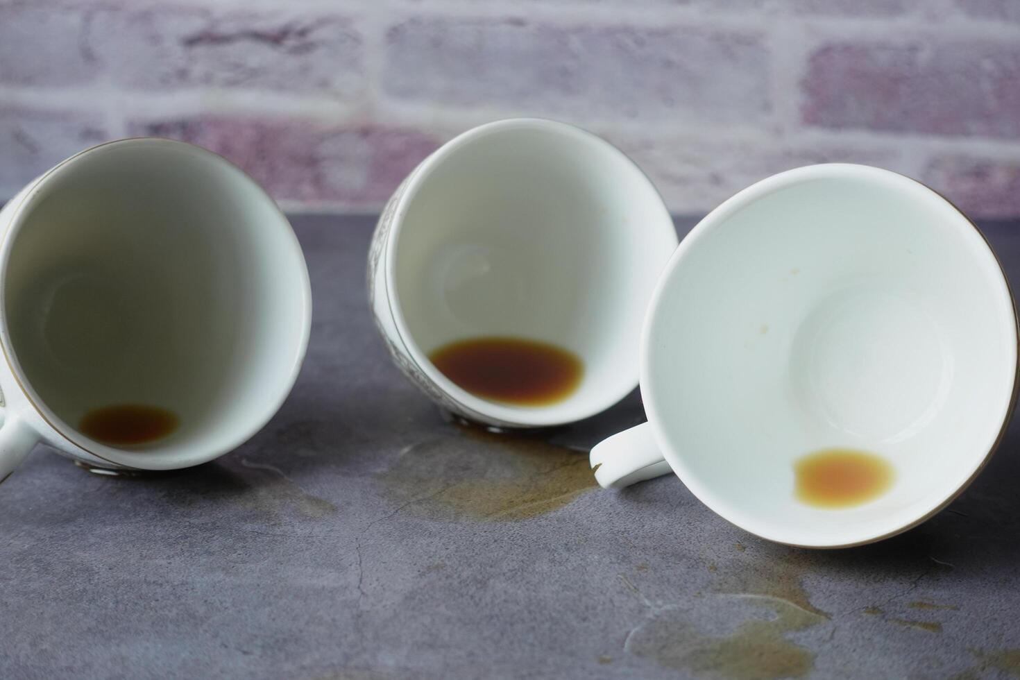 The table is cluttered with empty coffee cups, each still holding a few drops of leftover beverage photo