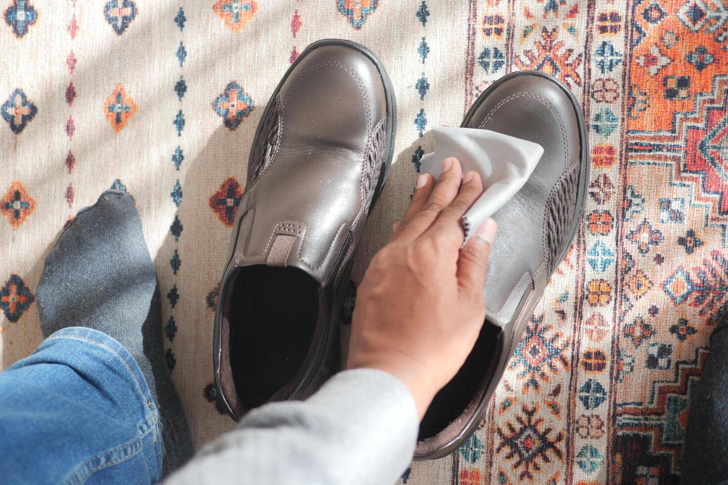 man wipes his leather shoes with a wet cloth photo