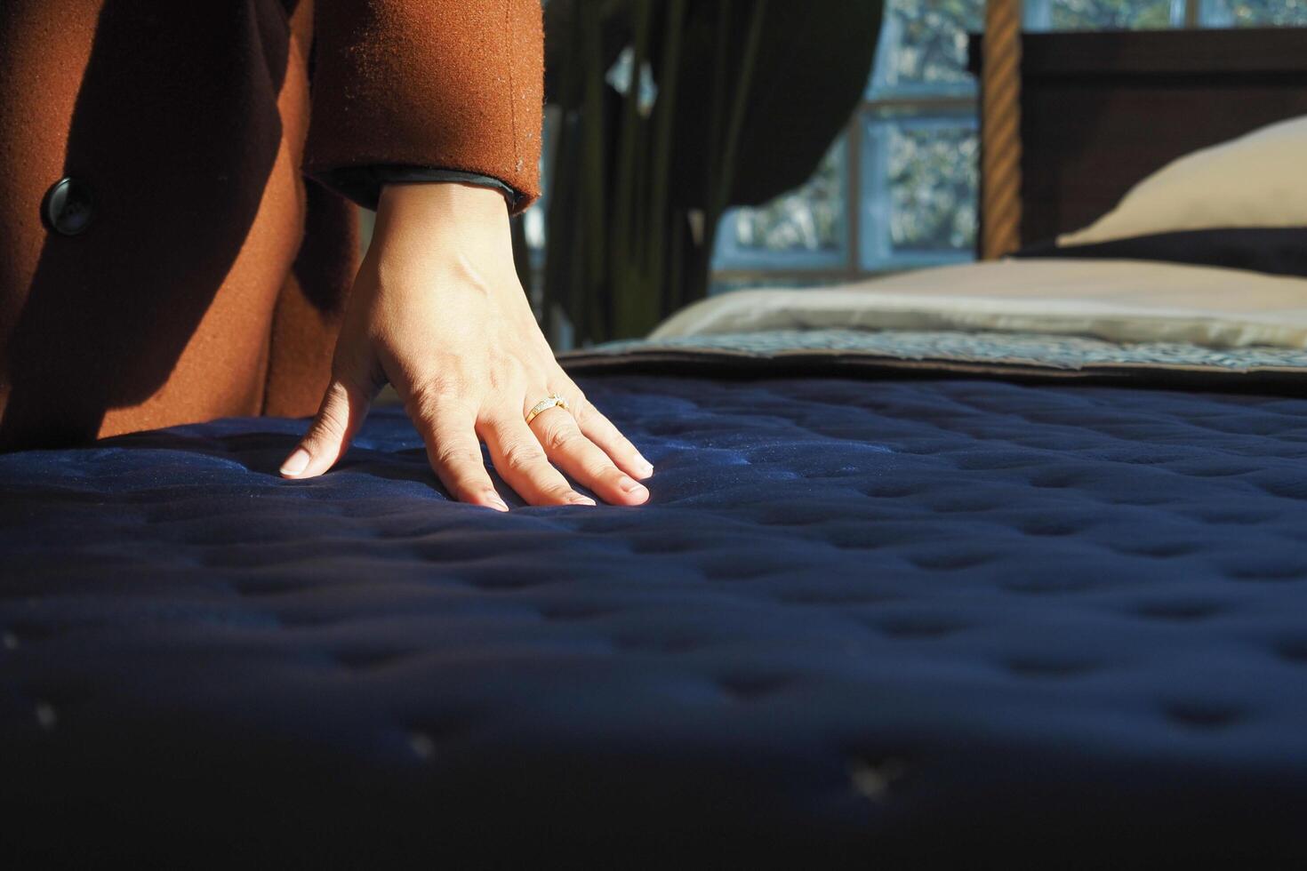 woman Hand touching and pressing orthopedic mattress on bed. photo