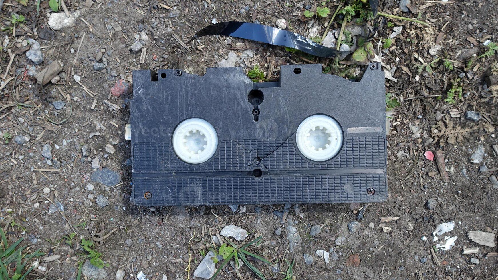 An old broken cassette abandoned on the ground. photo