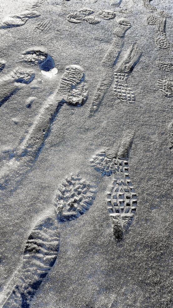 Footprints on a frozen lake in the mountains during a hike. photo