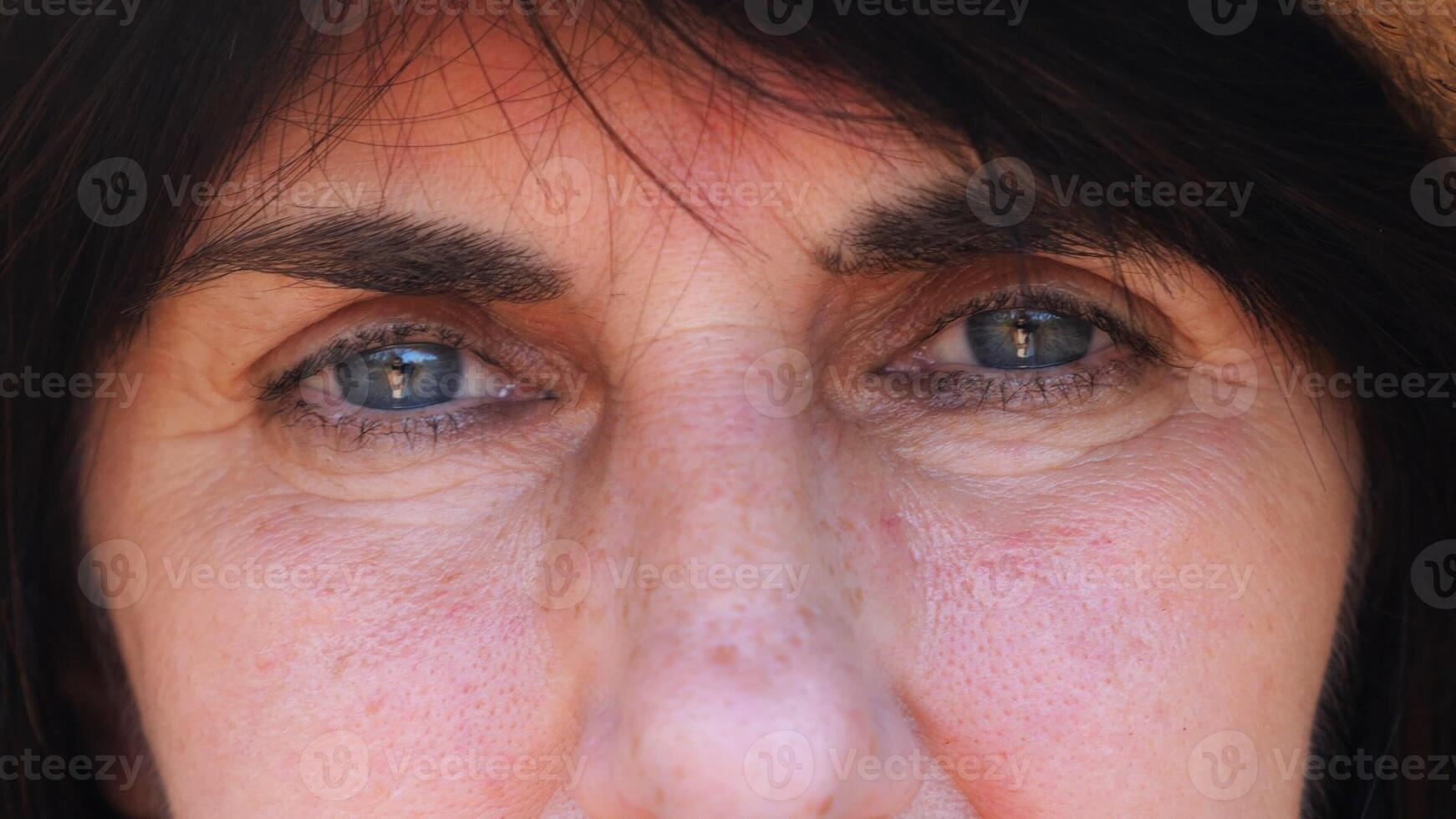 Close up to upset female face looking into camera with a disappointing sight. Upset facial expression of woman with black hair. Unhappy gaze of despairing adult lady. Slow mo photo