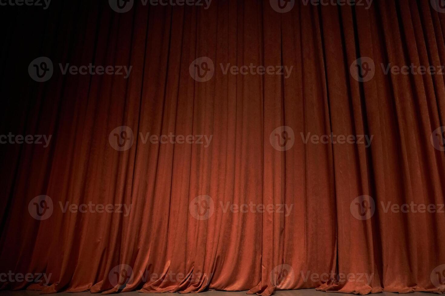 Orange closed curtain or drapes in theater with copy space. Theatrical performance concept. Spot of light on the curtain photo