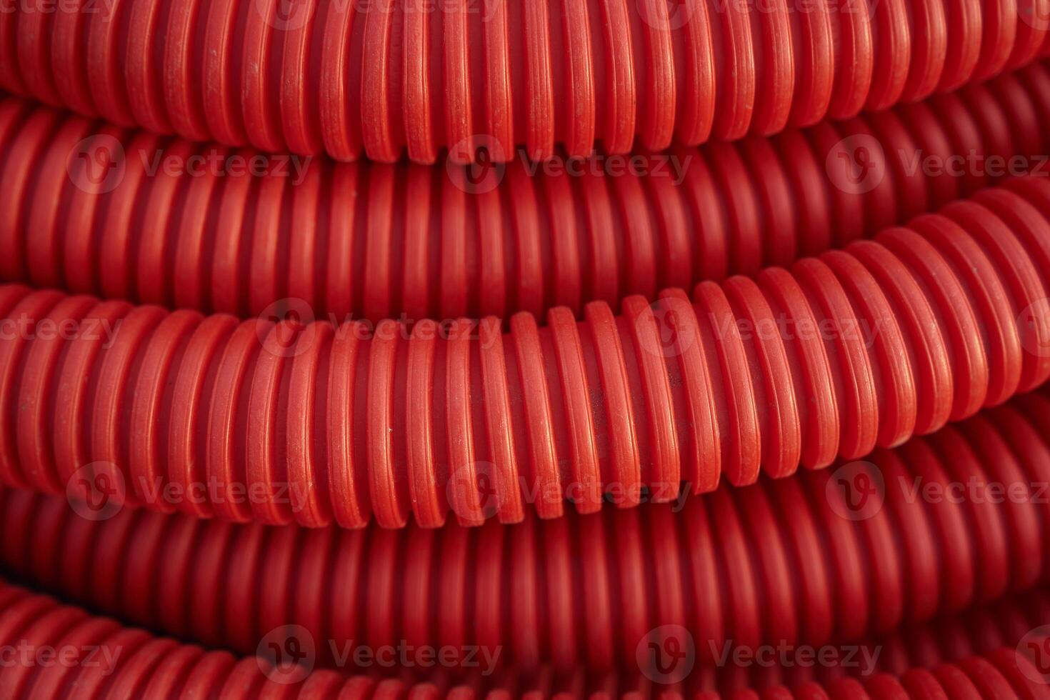 Corrugated for insulation cable of wires underground, plastic tube, electricity protection pipe for construction works, red corrugation close-up with copy space. photo