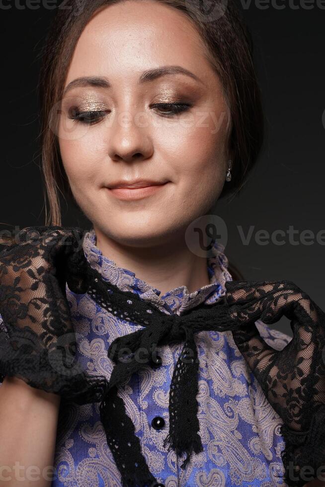 A close-up of a girl smiling, she adjusts the collar in lace gloves on a blue retro dress in the style of the 1900s. Historical fashion of the 19th century photo