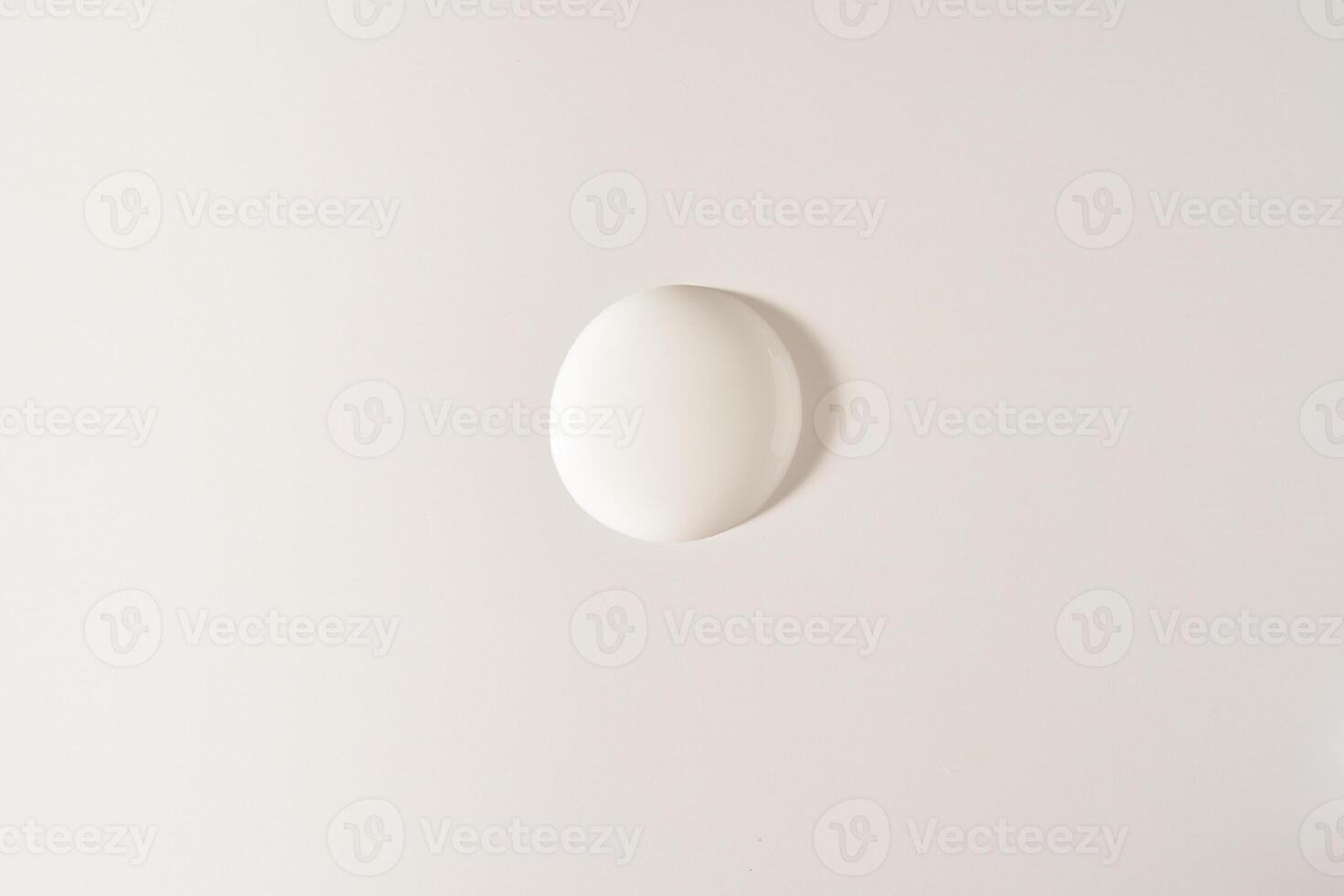 A round drop of cosmetic cream. A white creamy drop of skin care cream. A smooth drop isolated on a white background with space to copy photo