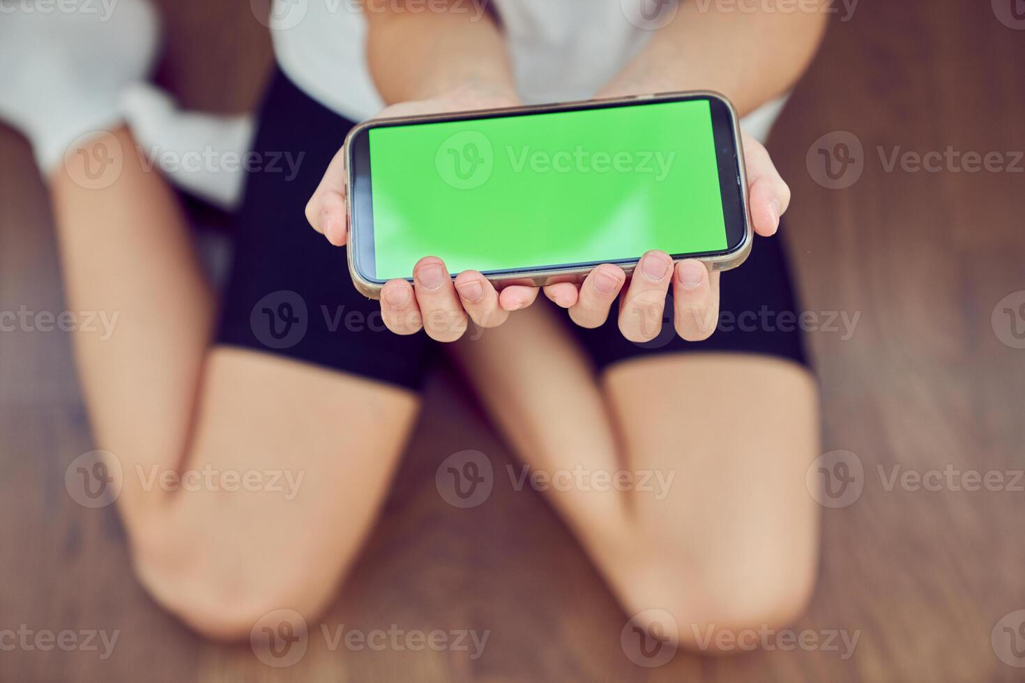 Close-up of children's hands using a phone with a green screen. A little girl is sitting on the floor and holding a smartphone with a colored key. photo