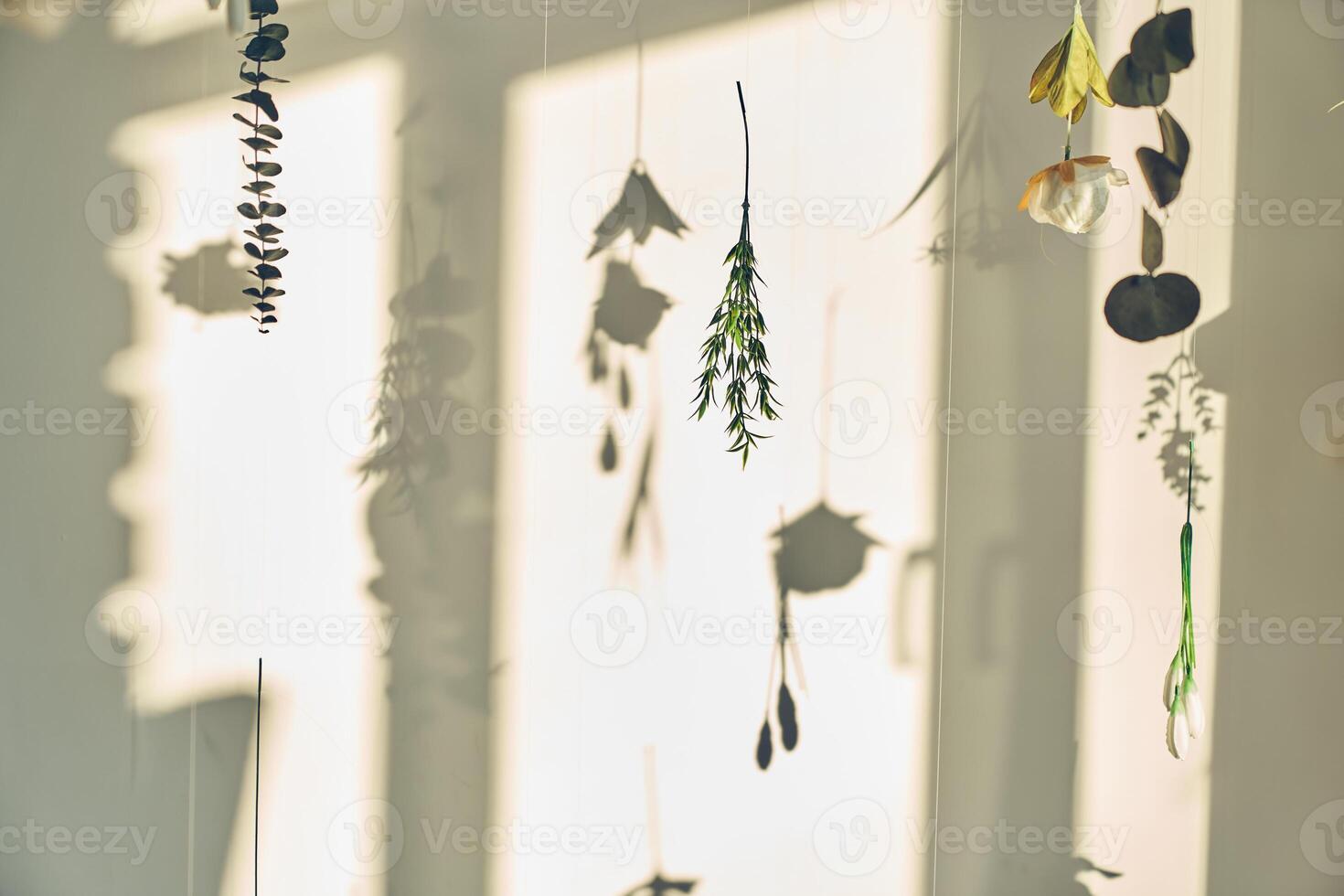 Mock up with artificial flowers levitating, hanging flowers on a white wall with window shadow. Background, backdrop with copy space. Template, mockup for your advertising, posters, product photo