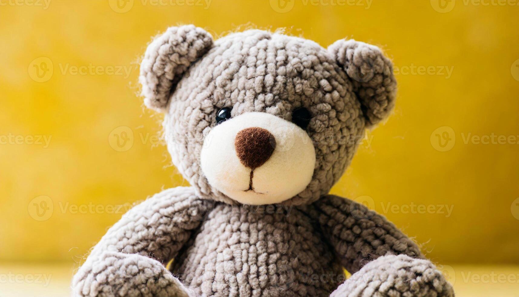 Beautiful teddy bear, wool toy sitting against bright yellow backdrop. photo