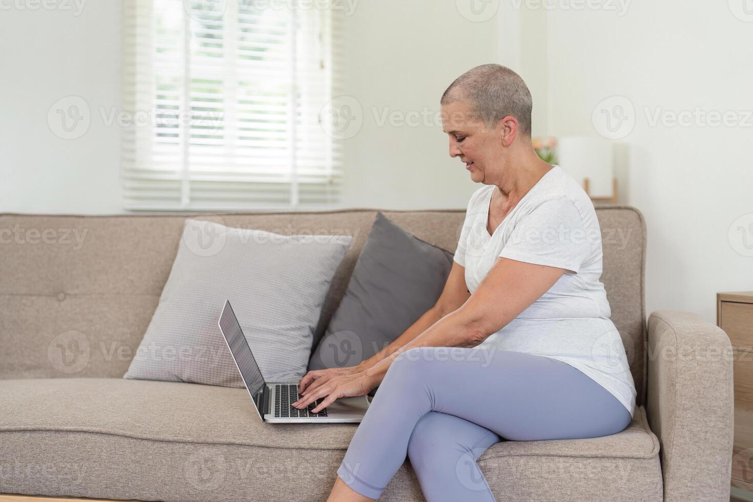 Elderly Woman Relaxing on Sofa While Using Laptop for Leisure and Entertainment in Modern Home Setting photo