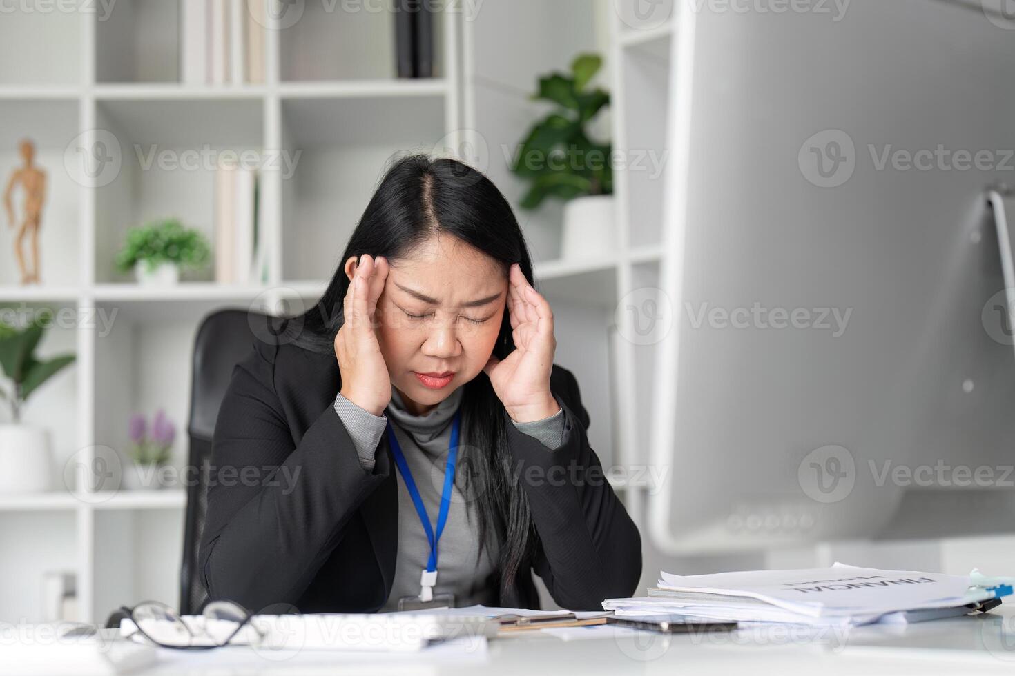 Stressed Middle-Aged Businesswoman Overwhelmed with Paperwork in Modern Office Setting, Experiencing Work-Related Stress and Fatigue photo
