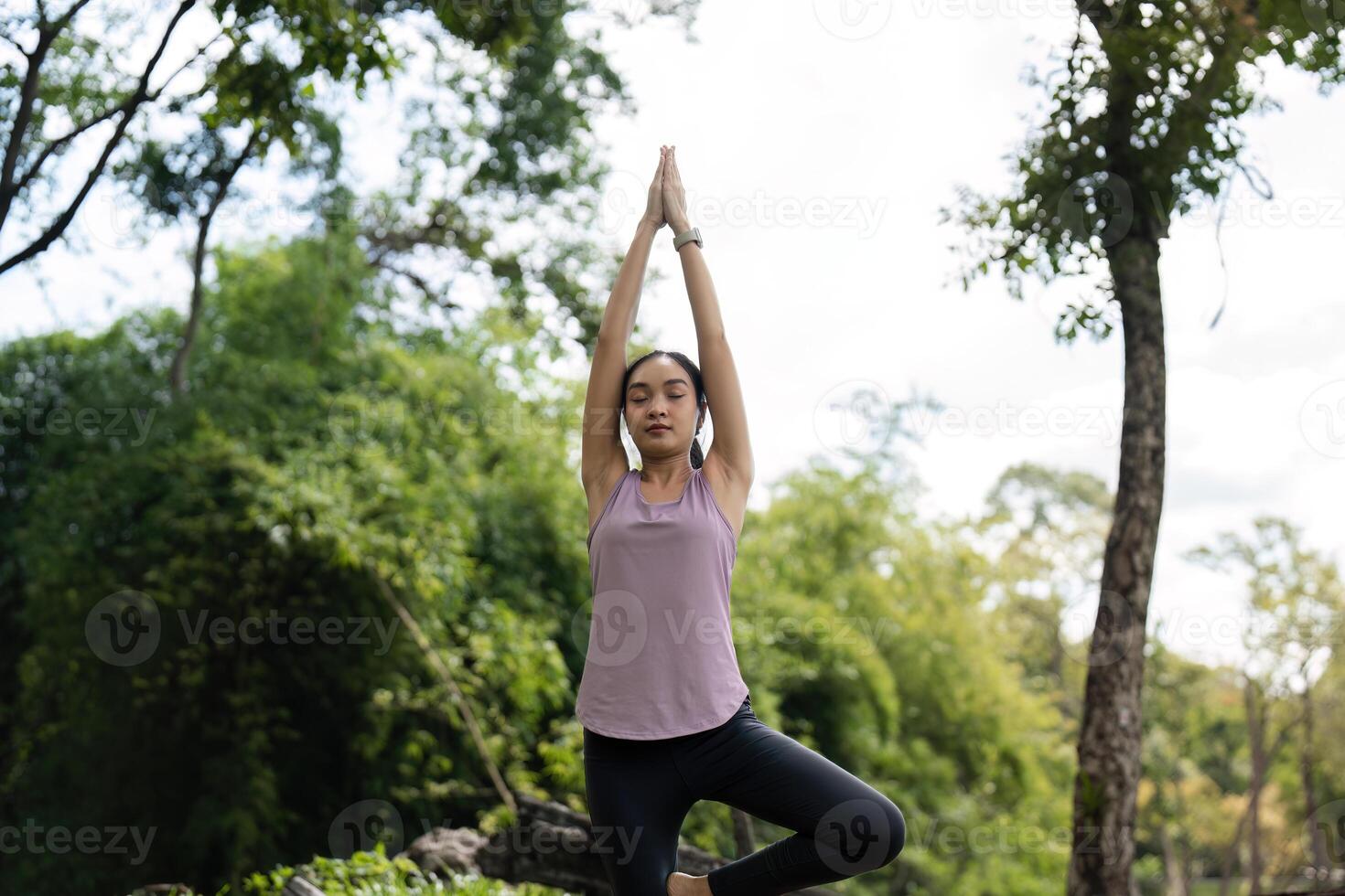 Woman Practicing Yoga Outdoors on Green Grass in a Peaceful Natural Park Setting with Trees and Blue Sky photo