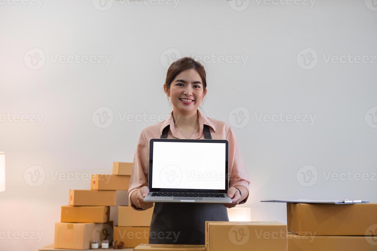 Woman Entrepreneur Selling Products Online from Home Office with Boxes of Inventory and Laptop photo