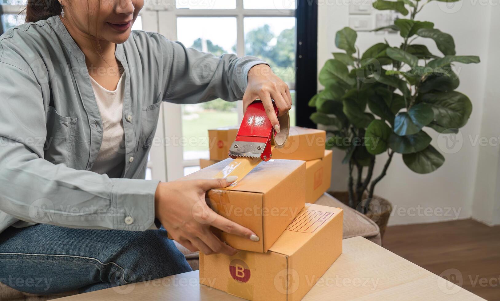 Young Woman Packing and Sealing Boxes for Online Sales in a Modern Home Office Environment photo