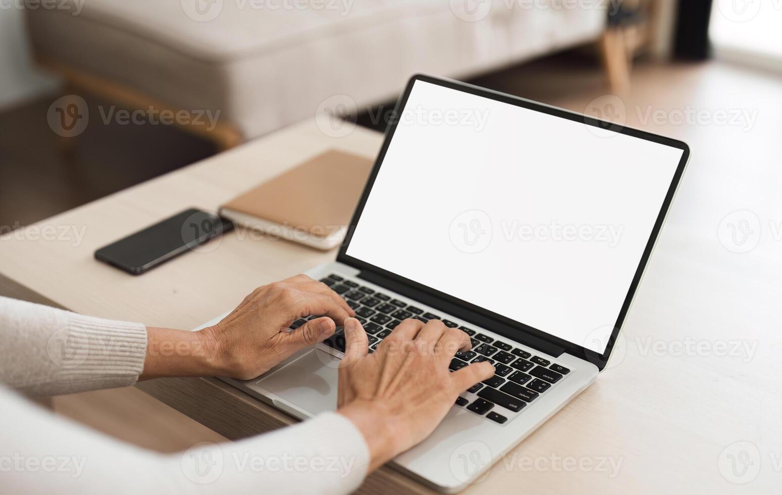 Young woman holding a laptop with a blank white screen on the table. Work space in your home living room or home office photo