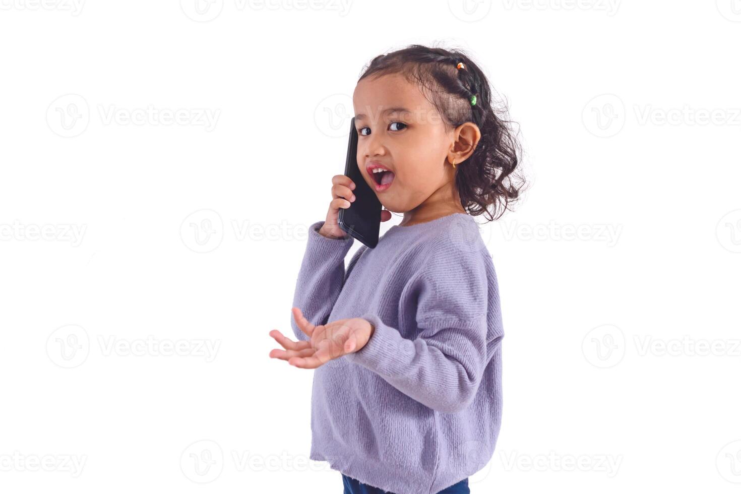 A happy little Asian girl talking on a cell phone, on a white background photo