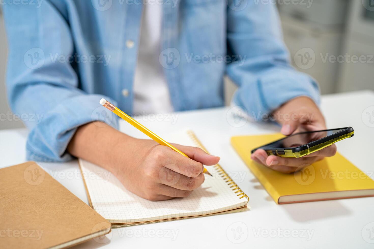 Teenage write in notebook and use mobile phone search data online to online learning university education. photo
