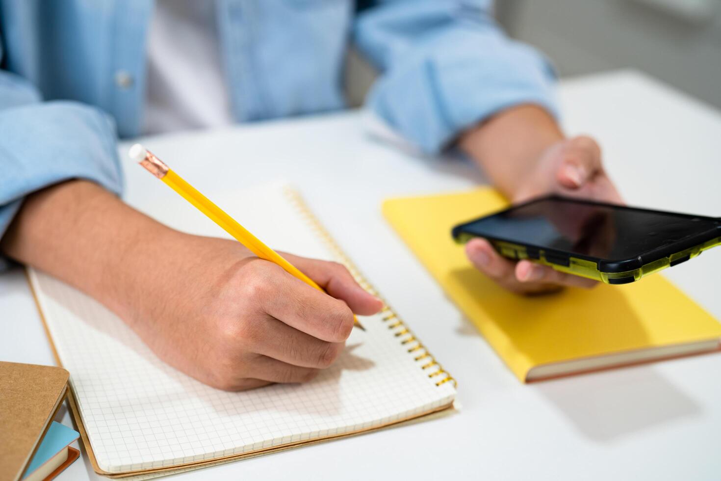 Teenage write in notebook and use mobile phone search data online to online learning university education. photo