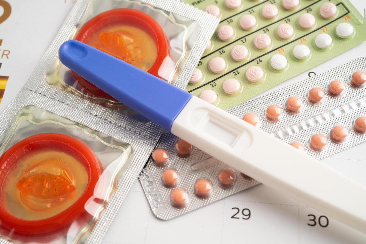 Pregnancy test and birth control pills on calendar, contraception health and medicine. photo