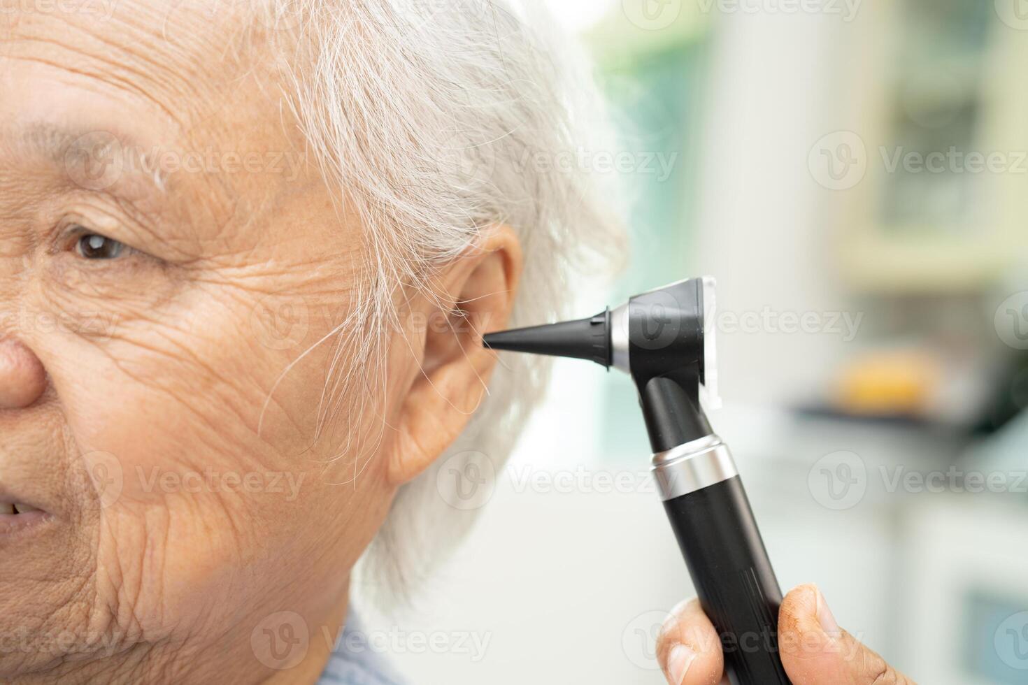 Audiologist or ENT doctor use otoscope checking ear of asian senior woman patient treating hearing loss problem. photo
