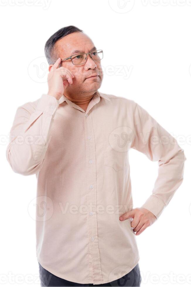 Asia man in a white shirt is looking to the left with his head tilted. He is wearing glasses and he is deep in thought photo