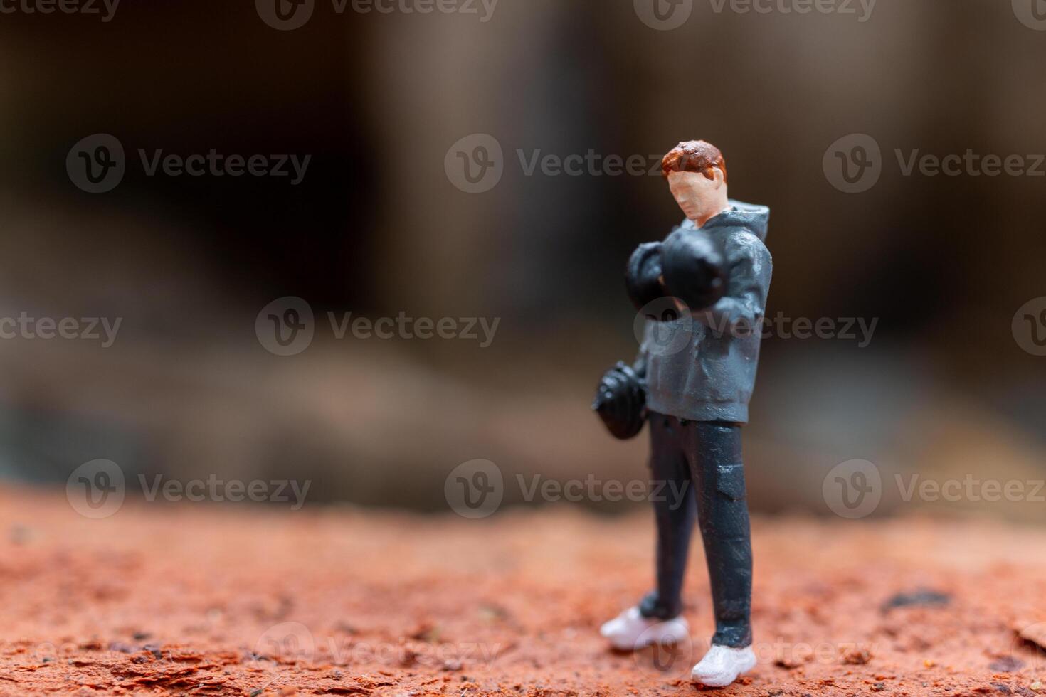 Miniature people, A man lifting dumbbells is set against a textured background photo