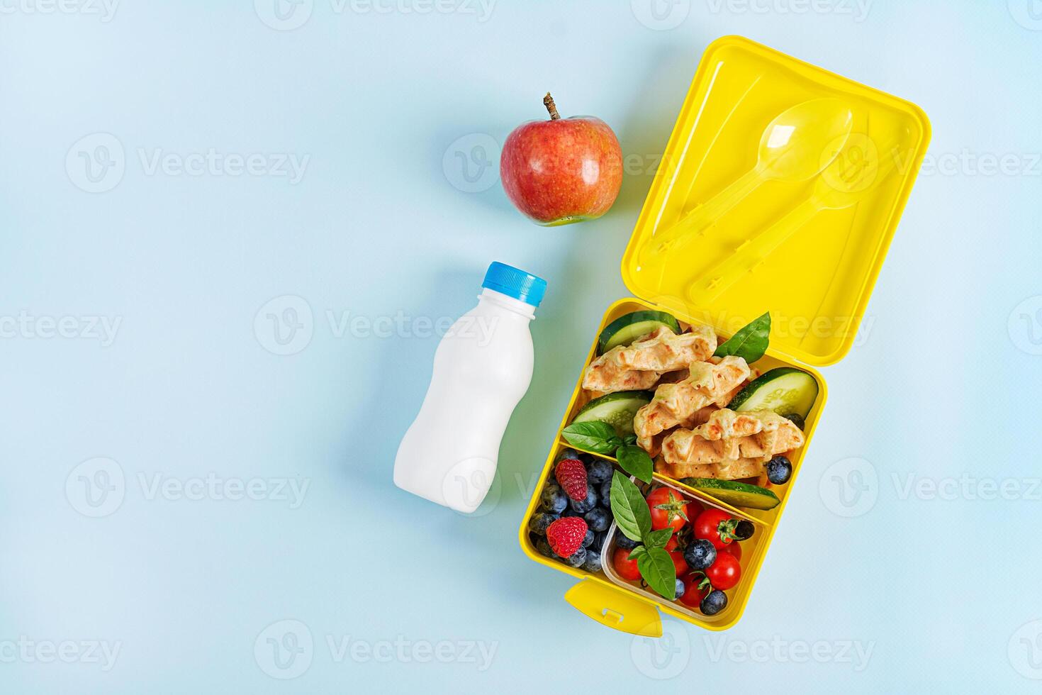 Kids lunch box with zucchini waffles, cucumber, cherry tomatoes and blueberries. Back to school breakfast background. Copy space. Top view, flat lay photo