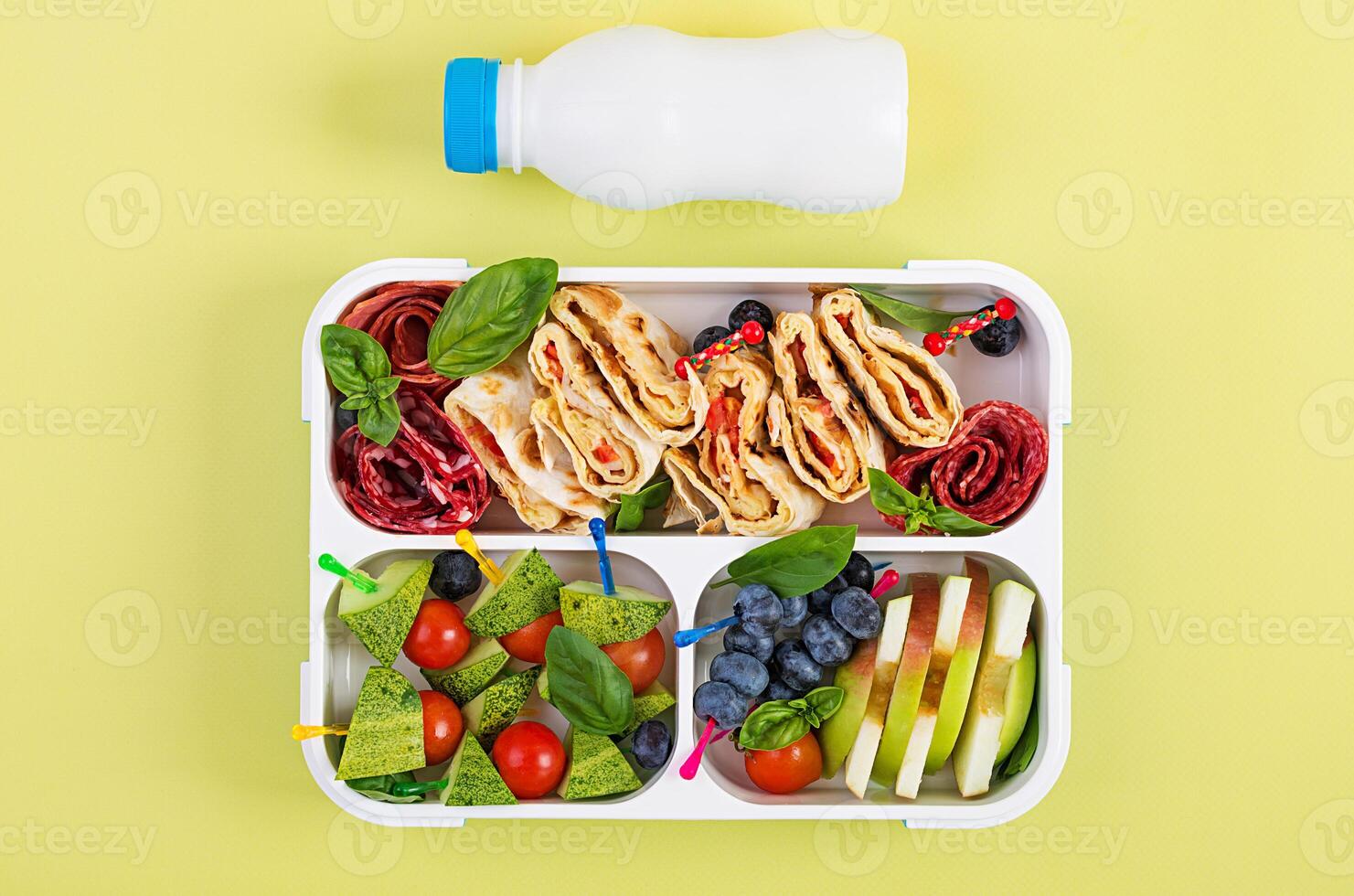 Kids lunch box with tortilla roll, sausage, cherry tomatoes and blueberries. Back to school breakfast background. Copy space. Top view, flat lay photo