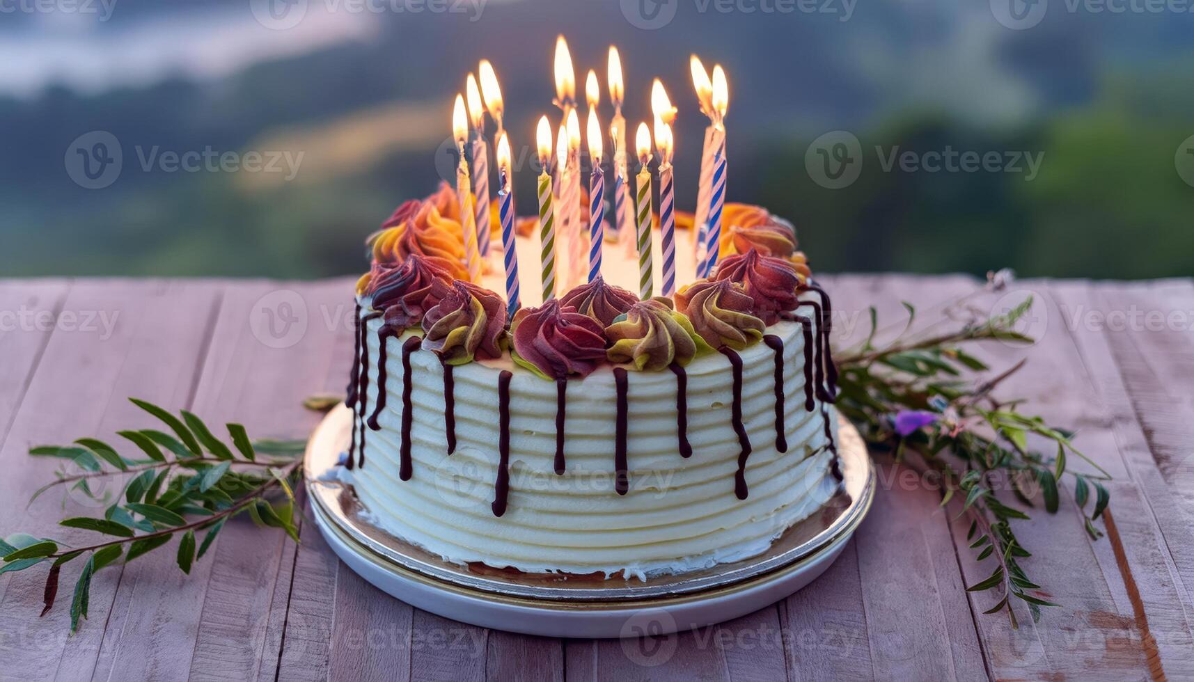 A white cake with chocolate drizzle and lit candles sits on a wooden table photo